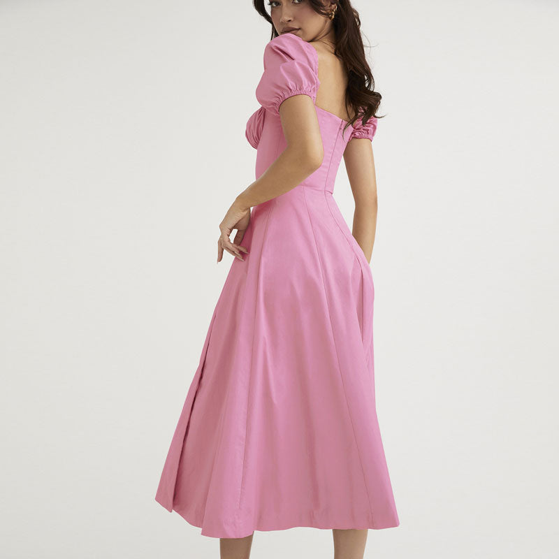 Woman wearing a pink midi dress with puff sleeves, showing the back view.