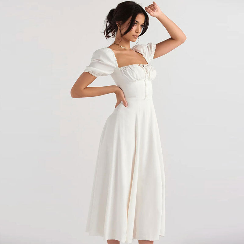 Woman in a white A-line dress with a ruched bodice and puff sleeves, posing.