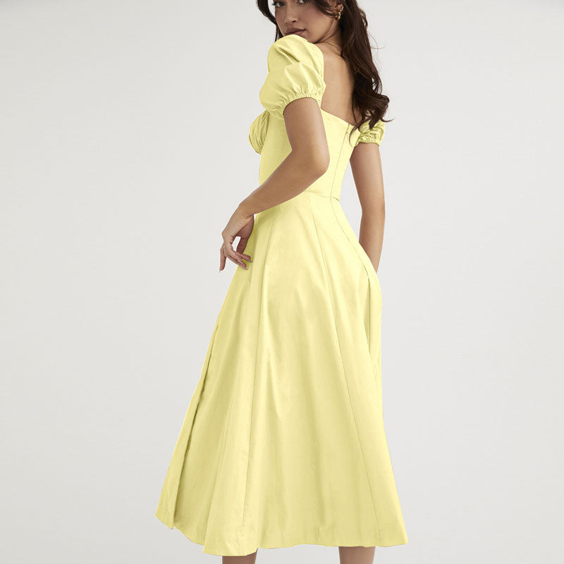 Back view of a woman in a yellow A-line midi dress with puff sleeves.