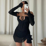 Woman taking a mirror selfie in a black sheer mesh mini dress with corset detailing and long sleeves.
