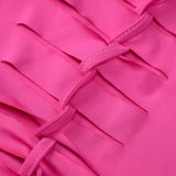 Close-up of the fabric of a pink dress, showing intricate cut-out and ribbon detailing.