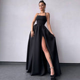 Woman in a black satin formal gown with a high slit and strappy back