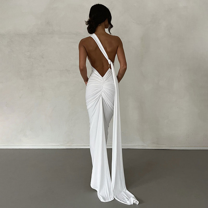 back view of a woman in a white ruched maxi dress with a deep v-back and long draped fabric