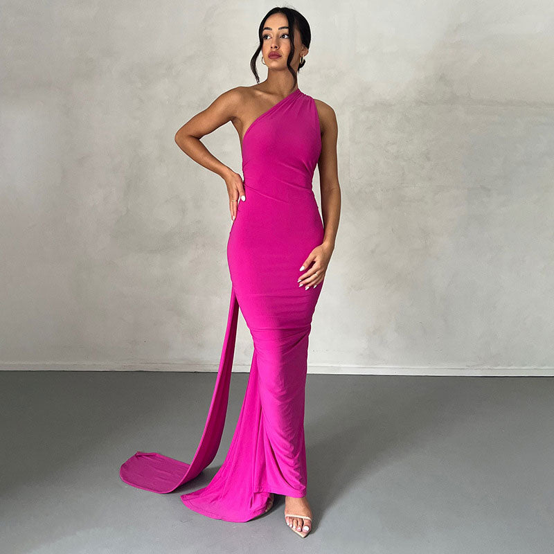 Woman wearing a floor-length fuchsia one-shoulder gown with a draped train.