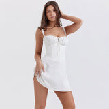 Woman wearing a white mini dress with a corset bodice and flared skirt, standing in a studio.