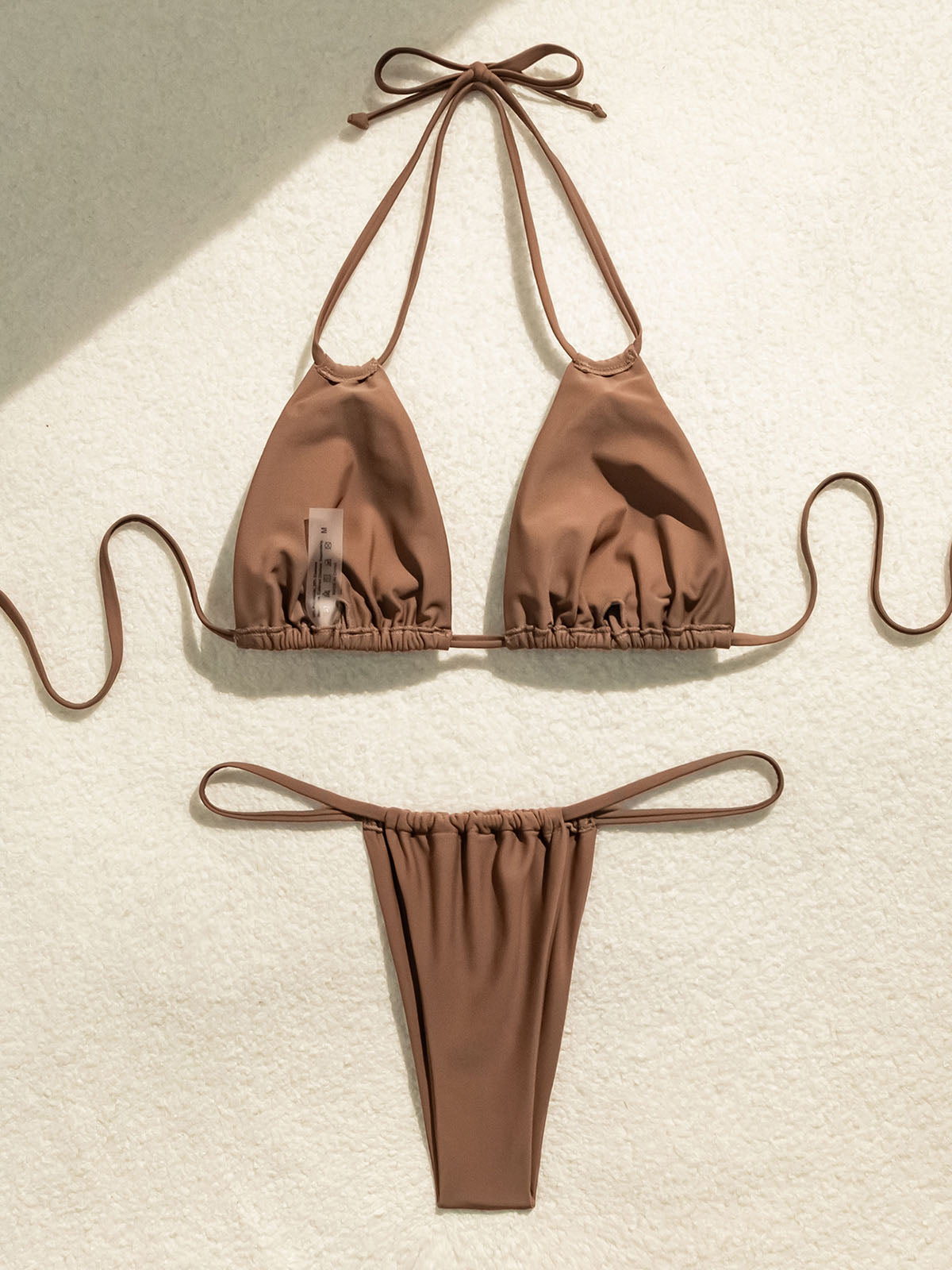Brown bikini top and bottom laid flat with tag visible