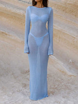 woman wearing a light blue sheer knit maxi dress with a cut-out detail and long sleeves on a beach