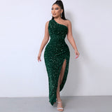 Full-length view of a woman in an emerald green sequined one-shoulder gown with a side slit, standing against a white backdrop.
