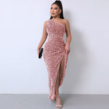 Woman wearing a rose gold sequined one-shoulder maxi dress with a high slit, holding a black clutch.