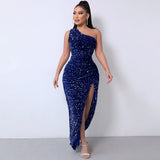 Full-length view of a woman in a navy blue sequined one-shoulder dress with a high slit, posing with hands on hips.