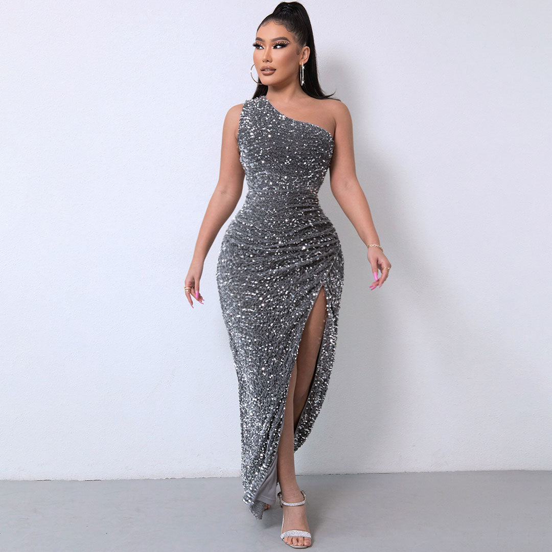 Woman wearing a shimmering grey one-shoulder sequined gown with a high slit.