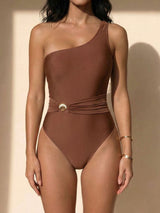Front view of a woman wearing a brown one-shoulder one-piece swimsuit with a cinched waist detail.