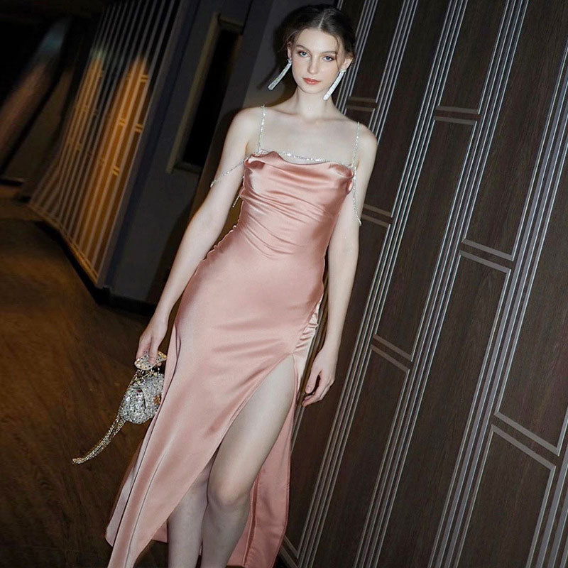 Woman wearing a pink satin slip dress with a high slit and sparkling straps
