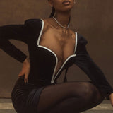 Close-up of a woman wearing a black velvet mini dress with a deep V-neckline and sparkling trim