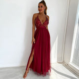 Woman in a long, deep red formal dress with a sequined bodice and a high slit, posing with one hand on her hip.