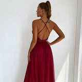 Back view of a woman in a deep red formal dress, highlighting the open back and halter straps.