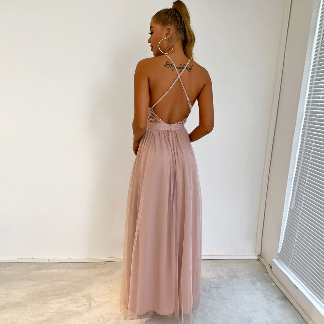 Back view of a woman in a blush pink formal dress with a sequined bodice and a crisscross back.