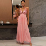 Woman wearing a pink sequined and chiffon evening gown with spaghetti straps and a deep V-neckline.