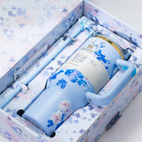 The light blue Stanley Quencher H2.0 Tumbler nestled inside its floral-patterned gift box, complete with a straw and bow accent.