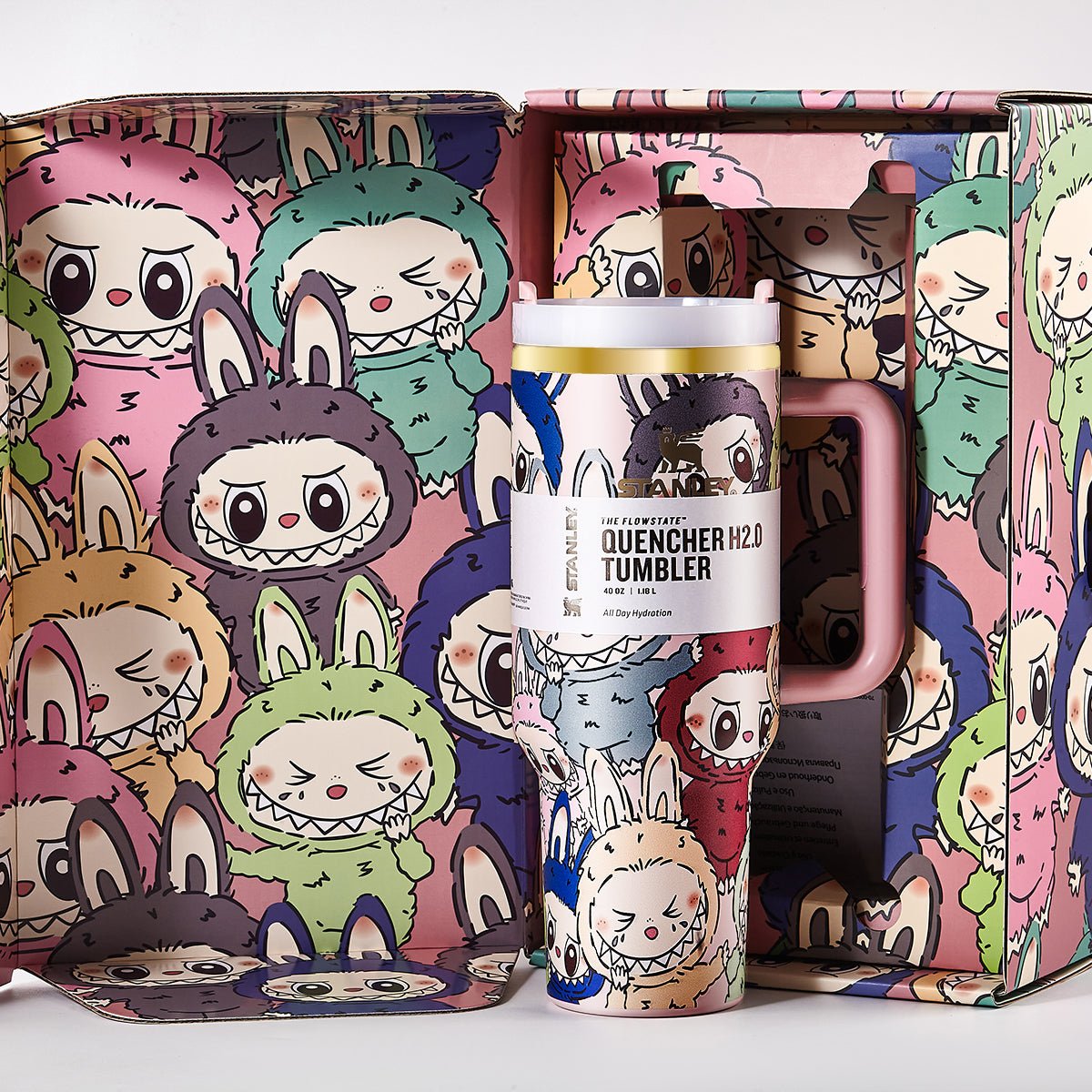Open gift box revealing the Stanley Quencher H2.0 Tumbler surrounded by cartoon character illustrations