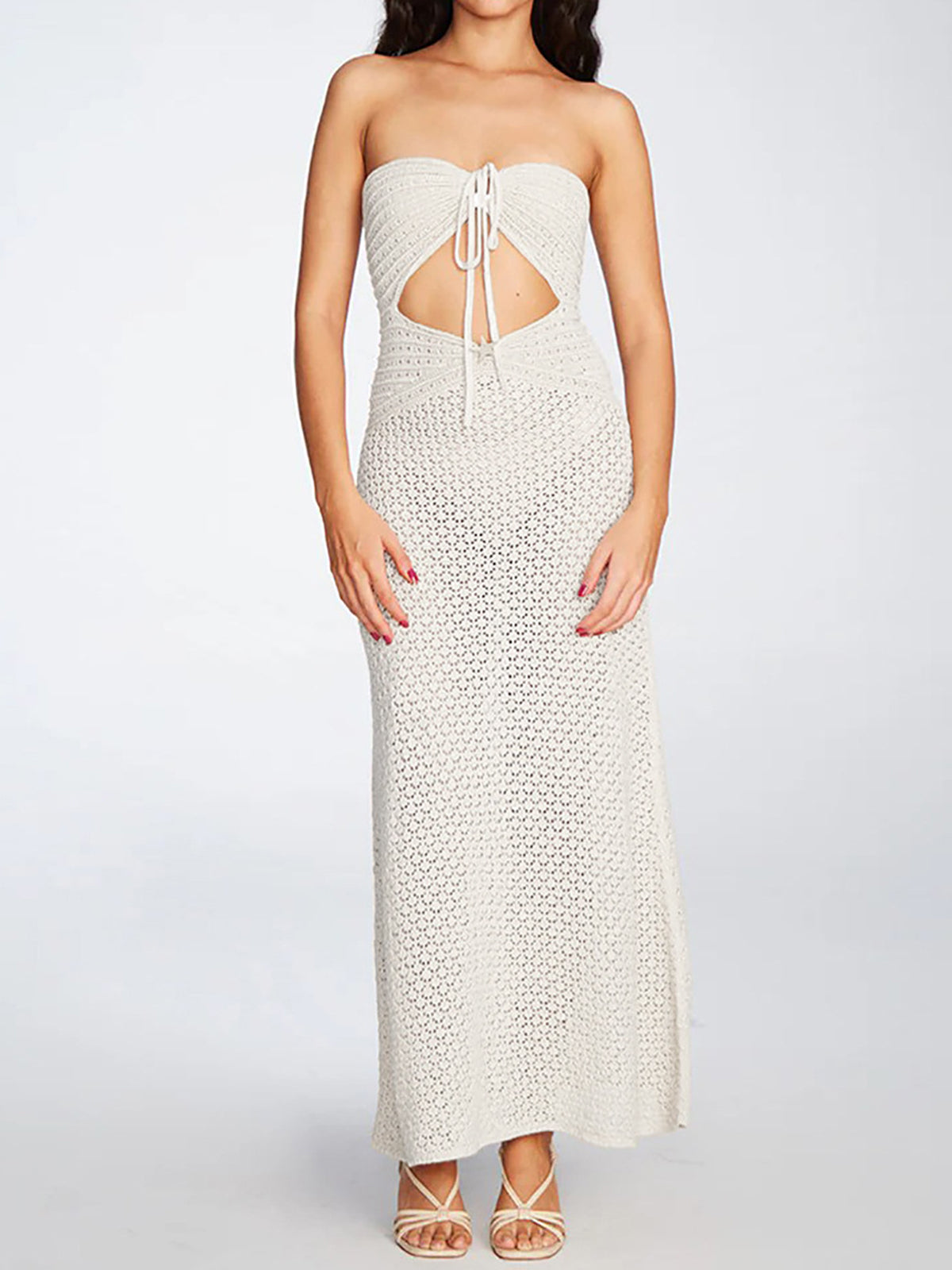 Front view of a woman wearing a white crocheted strapless maxi dress with a cutout detail at the bust and tie closure