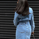 Back view of a woman wearing a blue denim shirt dress.