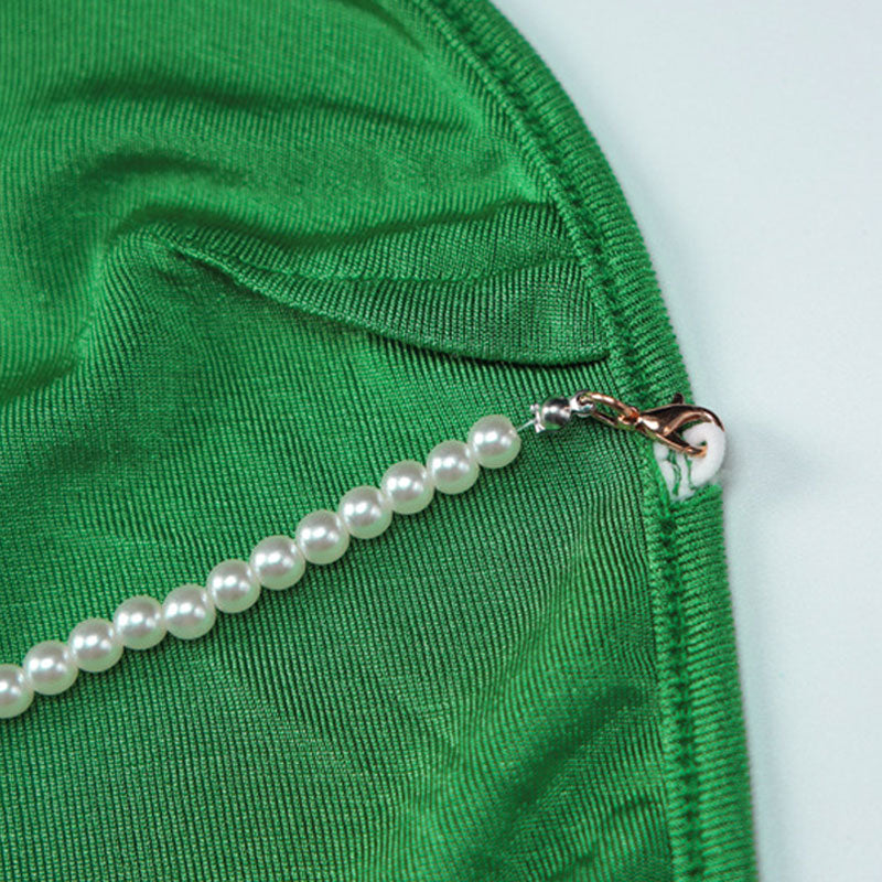 Close-up of the pearl strap detail on a green velvet dress.
