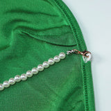 Close-up of the pearl strap detail on a green velvet dress.