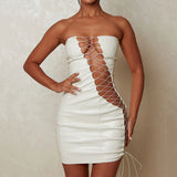 Woman wearing a white strapless faux leather mini dress with lace-up detailing on the front and sides