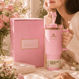 Pink Stanley tumbler with a woman holding it, surrounded by flowers and a pink box.