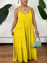 Woman wearing a yellow tiered maxi dress with spaghetti straps and a v-neckline, holding a mint green handbag.