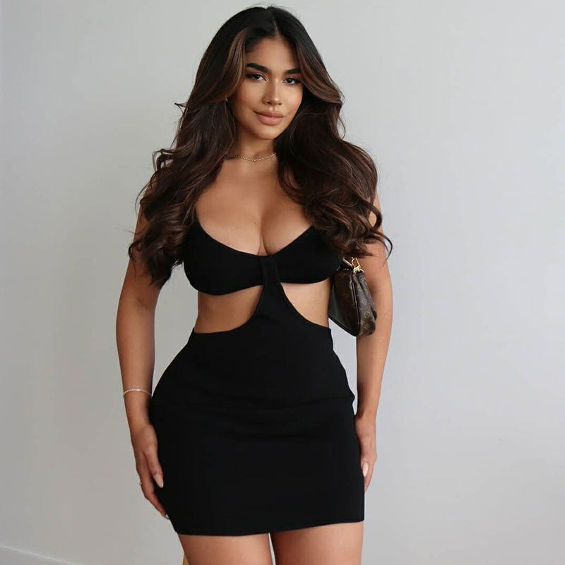 Woman wearing a black mini dress with cut-out details and spaghetti straps.
