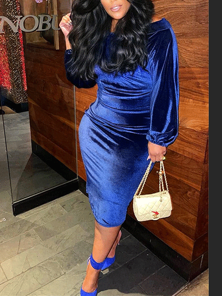 woman in a royal blue velvet off-the-shoulder midi dress with balloon sleeves, standing indoors
