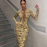 Woman wearing a yellow and brown zebra print midi dress with a lace-up neckline and long sleeves, standing on a modern staircase.