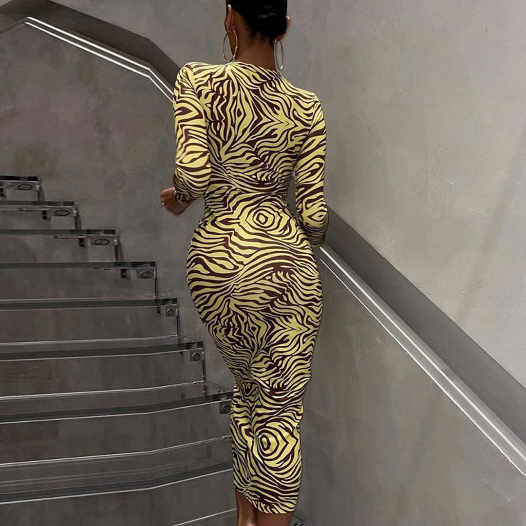 Rear view of a woman in a fitted zebra print midi dress with long sleeves.