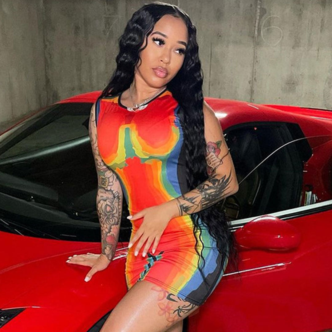 woman in a colorful abstract print bodycon dress leaning against a red car