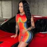 woman in a vibrant abstract print bodycon dress posing next to a red car