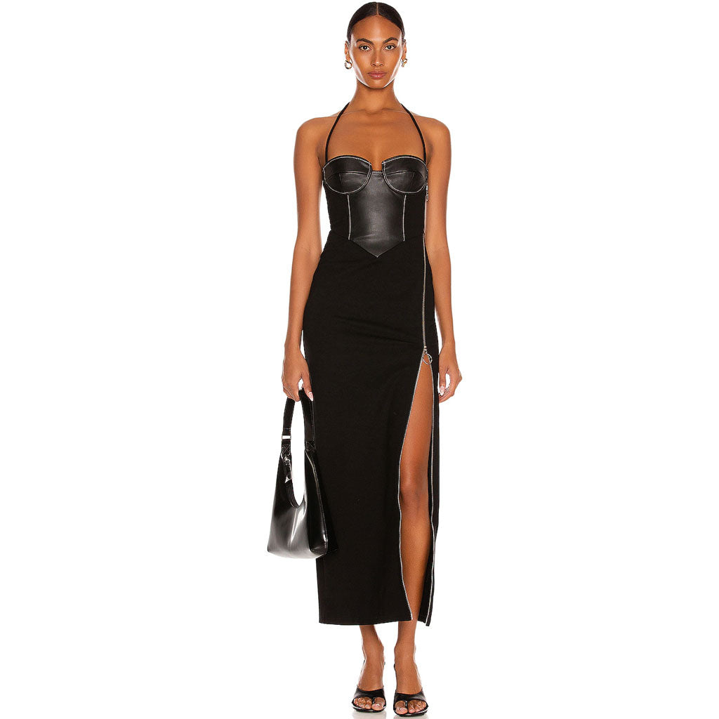 Full-length studio shot of a woman wearing a black halter dress with a corset bodice and thigh-high slit, holding a black handbag.