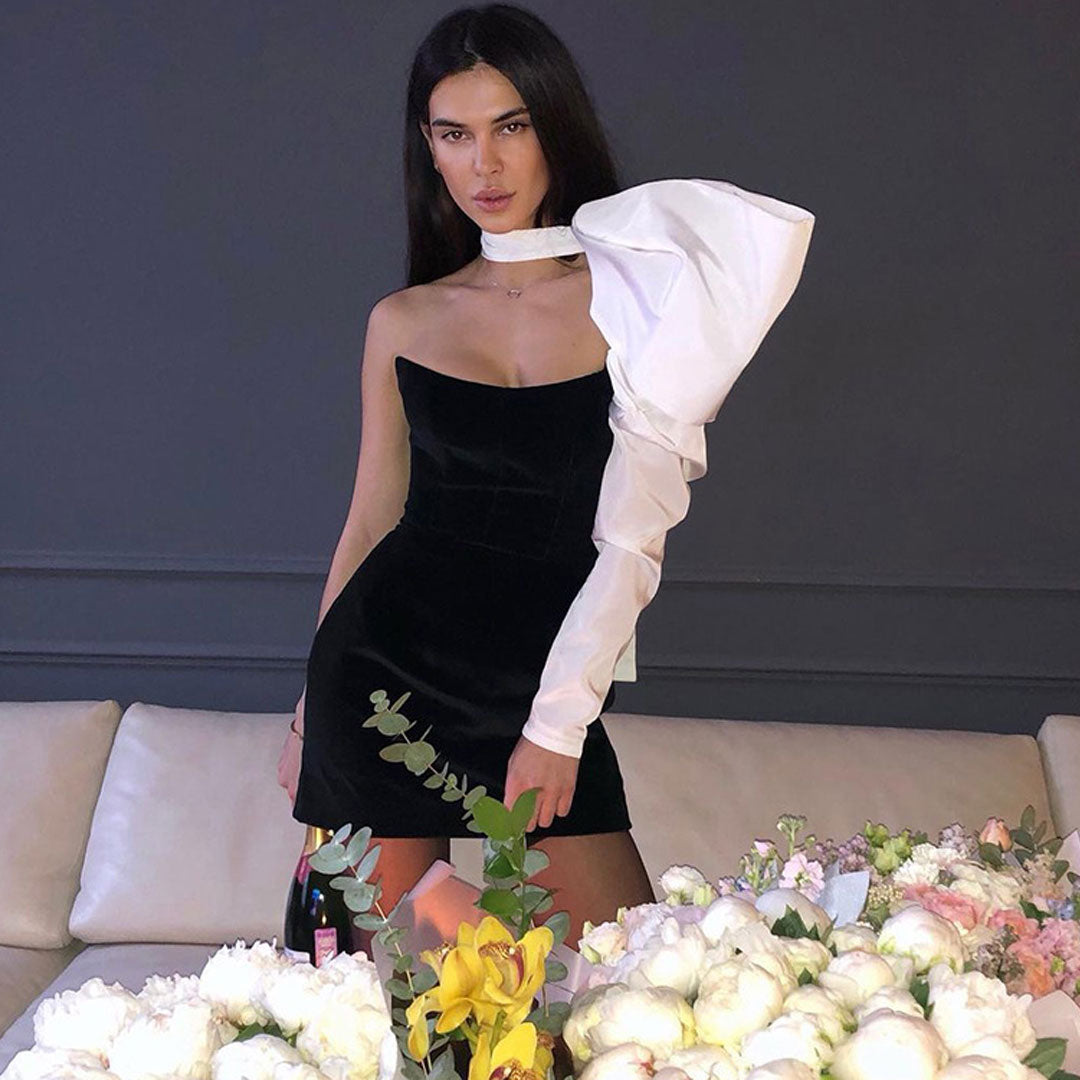 model posing in black velvet mini dress with dramatic white sleeve