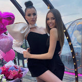 two women in black dresses, one with a large white bow sleeve