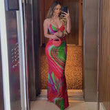 Woman wearing a colorful abstract print maxi dress with cut-out details and a halter neckline.
