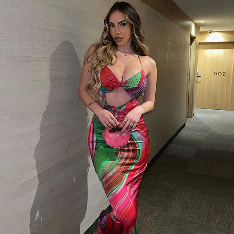 Woman in a hotel hallway wearing a vibrant abstract print maxi dress with cut-out details.