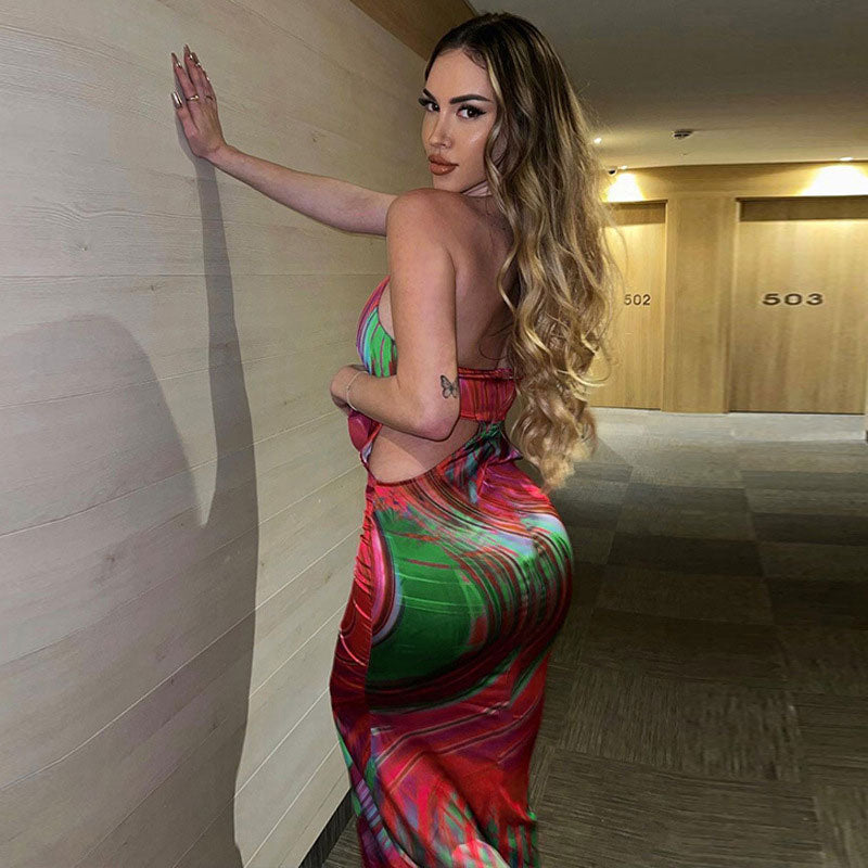 Woman posing in a hotel hallway, showing the back of a colorful abstract print maxi dress.