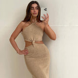 Woman taking a mirror selfie in a beige knit midi dress with cut-out detailing and a halter neckline.