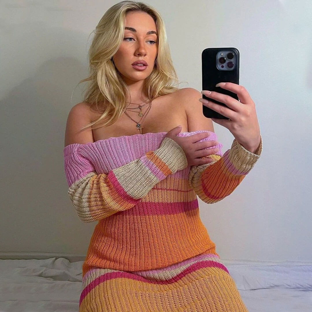 woman in a striped knit dress, showing off the off-the-shoulder neckline