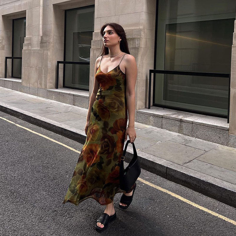 Woman walking down a street wearing a floral print midi slip dress.