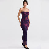 Full body shot of a woman in a long, dark purple floral print dress with a side slit.