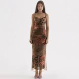 Woman wearing a long, brown, sheer mesh dress with a floral and animal print, featuring spaghetti straps and a thigh-high slit.