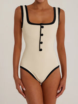 Woman wearing a cream and black ribbed one-piece swimsuit with button detailing