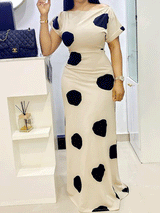 Front view of a woman posing in a cream and black polka dot maxi dress.